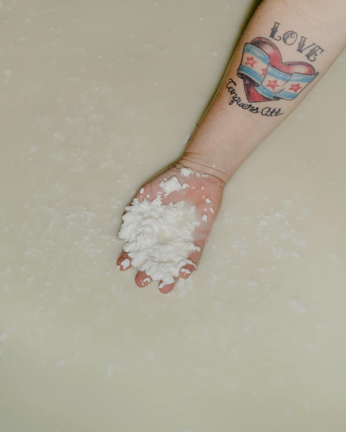 A hand pulls out the curds from whey.